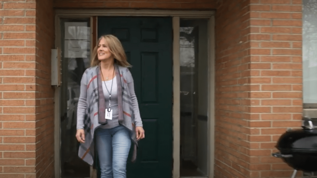 A volunteer leaving an apartment after dropping off a meal for Meals on Wheels and she is happy and smiling because she is proud to be a volunteer